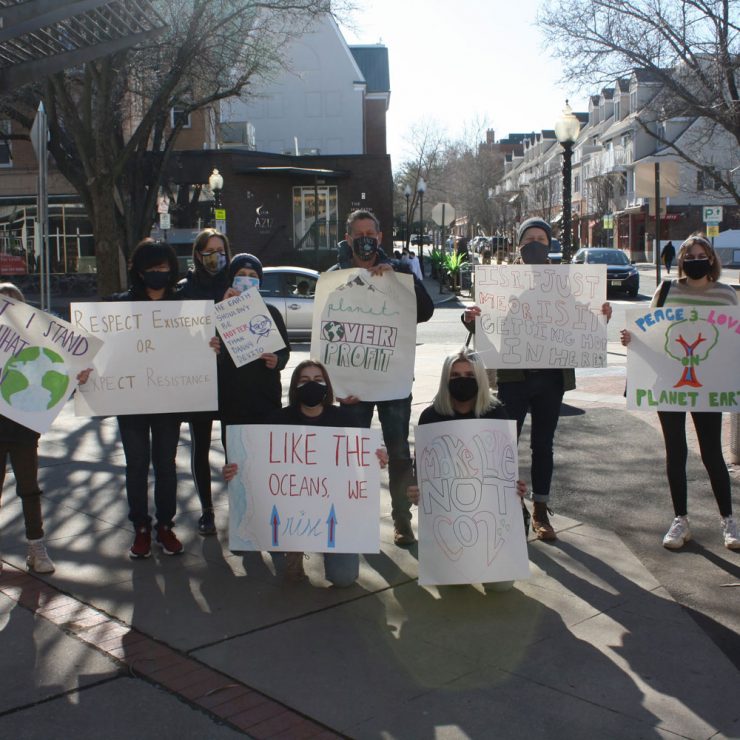A group of people standing with signs advocating for climate action on the street.