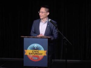 Eric Liu standing at a Civic Saturday podium and speaking.