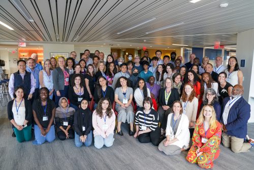 A group of 50 diverse people standing together and smiling at the camera.