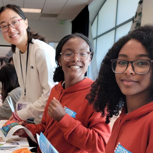 Three young people working on a project at a table and smiling